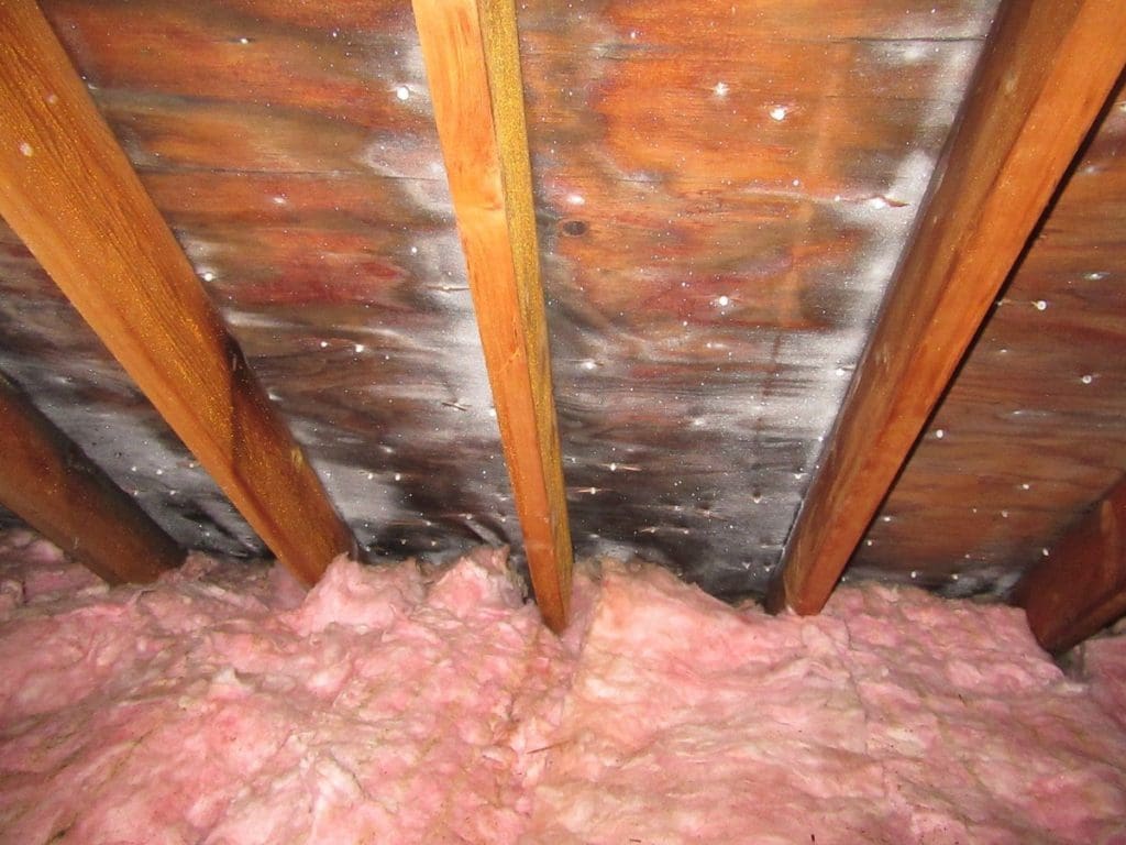 The inside of a roof with ice build-up, that is causing structural damage and decay.